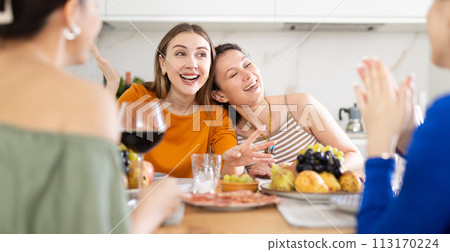 Girlfriends chatting and drinking wine in kitchen Girlfriends chatting and drinking wine in kitchen 113170224