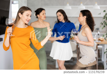 Cheerful woman dancing with wine glass at friendly house party Cheerful woman dancing with wine glass at friendly house party 113170239