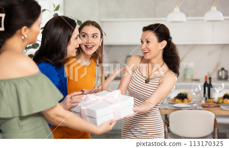 Happy woman receiving gift from besties at birthday bash 113170325