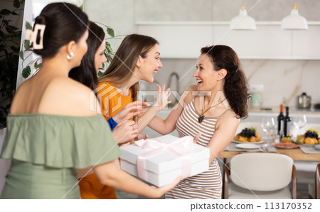 Three women have arrived for birthday celebration and presenting gift to birthday woman 113170352