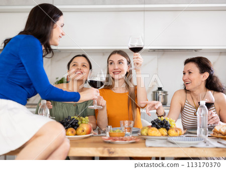 During gathering with friends, woman sit on table, enjoying food and wine, chatting, talking 113170370