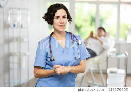 Woman beautician wearing blue overall posing in clinic of esthetic medicine Woman beautician wearing blue overall posing in clinic of esthetic medicine 113170405