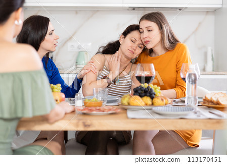 Female friends comforting upset woman at home gathering 113170451