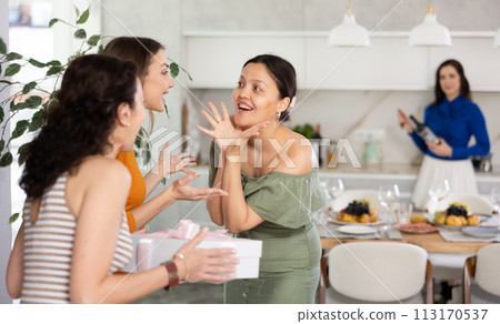 Two women have arrived for birthday celebration and presenting gift to birthday woman Two women have arrived for birthday celebration and presenting gift to birthday woman 113170537