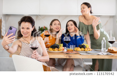 Excited woman taking selfie with besties during home celebration Excited woman taking selfie with besties during home celebration 113170542
