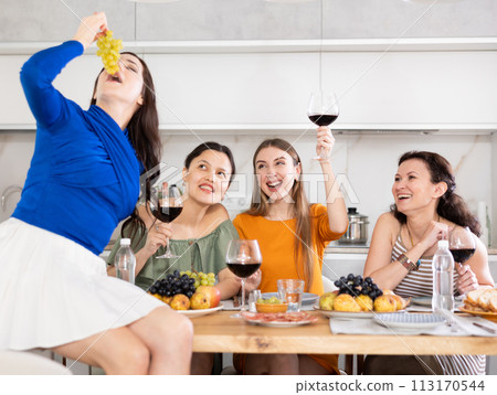 Girlfriends chatting and drinking wine in kitchen Girlfriends chatting and drinking wine in kitchen 113170544