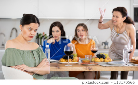 Offended Asian woman listening to disapproval of friends at house party Offended Asian woman listening to disapproval of friends at house party 113170566