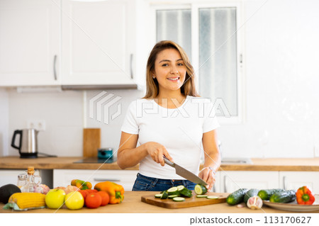 Positive young latin american girl cooking salad in home kitchen 113170627