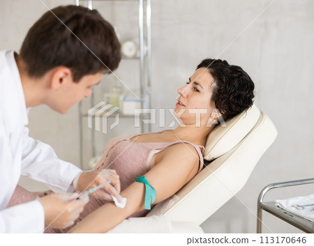 Middle-aged woman having vein injection lying on clinical chair 113170646