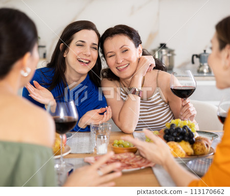 Girlfriends chatting and drinking wine in kitchen Girlfriends chatting and drinking wine in kitchen 113170662