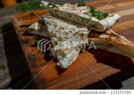 Lavash envelope with cottage cheese and green onions on a wooden board Lavash envelope with cottage cheese and green onions on a wooden board 113171780