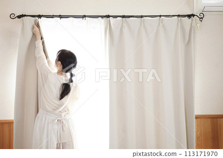 A woman in an apron changing the curtains A woman in an apron changing the curtains 113171970