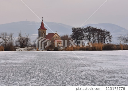 Beautiful old church of St. Linhart. Catholic temple village of Musov - Pasohlavky, Czech Republic. Photo of winter landscape with sunset on a dam New Mills (Nove Mlyny). 113172776