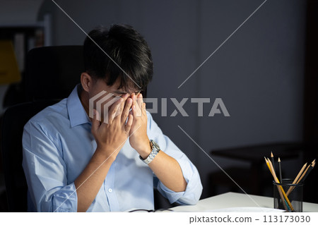 Businessman working overtime at his office makes his eyes tired. 113173030