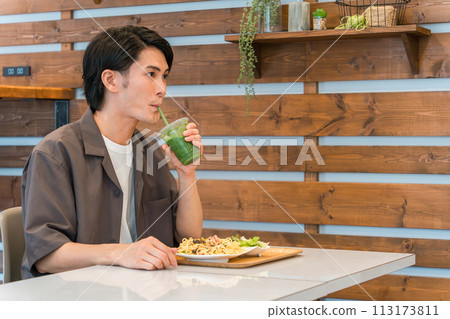 Young man drinking green smoothie while eating lunch at a cafe (enzyme/healthy/dietary fiber/healthy food) 113173811