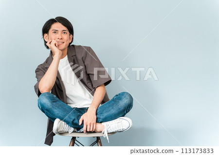 A refreshing man wearing sneakers and jeans sitting on a chair 113173833