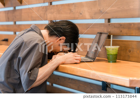 A young Asian man is shocked and depressed at a cafe/coworking space. 113173844