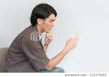 Young Asian man using a smartphone (searching, serious, worrying, thinking, researching) 113173893