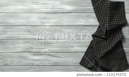 Gray wooden table with balck and white dark linen kitchen towel or textile napkin flat lay. Dark tablecloth on old vintage gray wood tabletop. Copy space for text. Can use as mock up for design. 113174373