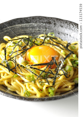 Abura-soba noodles topped with egg yolk, shredded seaweed, and green onions photographed against a white background 113174539