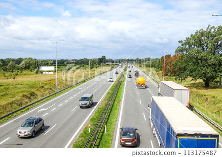 Aerial view of a highway with multiple lanes, showcasing the flow of traffic and the movement of cars and trucks, suitable for transportation infrastructure articles, traffic management reports 113175487