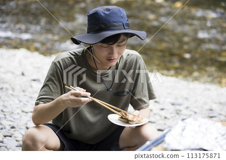 Outdoor image of a man frying ingredients in a frying pan 113175871