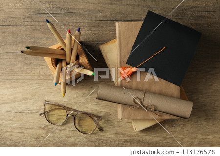 Graduate hat and books on wooden table 113176578