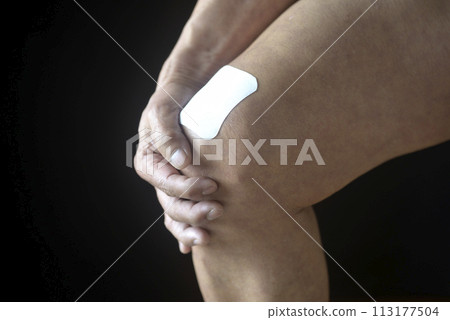 Poultice applied to the knee of an elderly man suffering from knee pain 113177504
