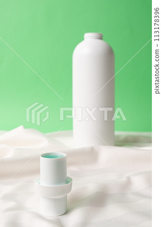 Natural liquid laundry detergent on a background of white satin fabric. 113178396