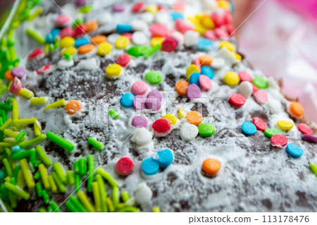 A cake with sprinkles on it is decorated with colorful sprinkles. 113178476