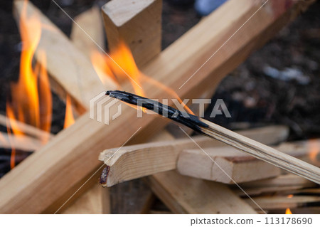 A fire burns in a campfire with a red fire in the background. 113178690
