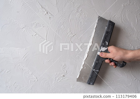 Applying decorative putty. White abstract texture of surface covered with putty 113179406