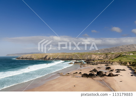 Durness Beach in Scotland, with azure waters, golden sands, dark rocks, surrounded by cliffs and sky 113179883