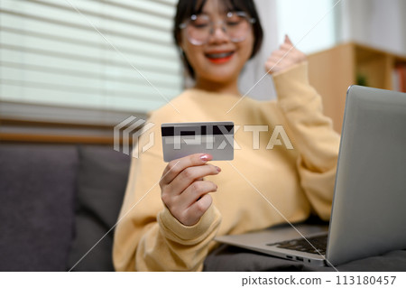 Happy young woman holding credit card celebrating victory or success Happy young woman holding credit card celebrating victory or success 113180457