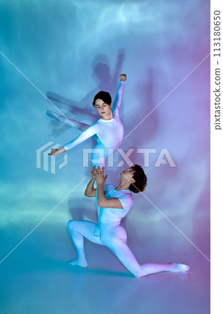 Contemporary ballet duo mid-performance, male dancer lifting female dancer against colorful gradient background with light play. Contemporary ballet duo mid-performance, male dancer lifting female dancer against colorful gradient background with light play. 113180650