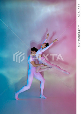 Two ballet dancers in dynamic pose, male supporting his female partner, against gradient neon-lit studio background. 113180657