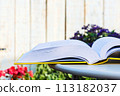 Opened book on table in flower summer garden 113182037