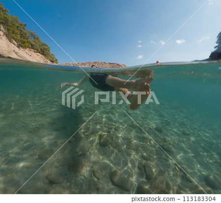 Young male on holidays enjoy floating on a crystal clear water beach of Antalya Turkey. Man swimming with open arms. Relax and tranquility Young male on holidays enjoy floating on a crystal clear water beach of Antalya Turkey. Man swimming with open arms. Relax and tranquility 113183304
