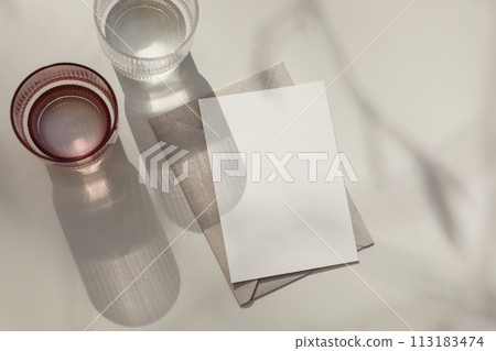 Two glasses of sparkling crystal water on beige background. Direct sun shine. Cocktail drinks top view. Sunlight long strong shadow, refraction patterns. Summer reflection effect. Greeting card mockup 113183474