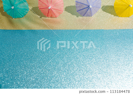 Abstract beach with glitter paper sand and water and cocktail umbrellas. Summer aesthetic mockup template background on a tropical beach holiday Abstract beach with glitter paper sand and water and cocktail umbrellas. Summer aesthetic mockup template background on a tropical beach holiday 113184478