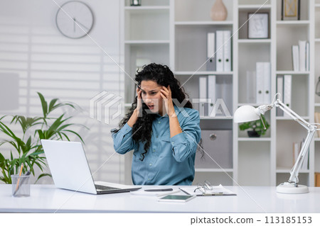 Worried Hispanic businesswoman receiving bad news while working from her home office, showing confusion and stress. 113185153