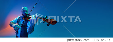 Concentrated bearded bald man, musician playing violin against blue background in neon with mixed light 113185283