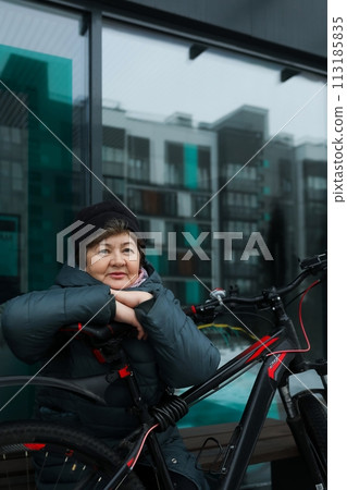 Mature European woman goes for a walk with a bicycle in winter Mature European woman goes for a walk with a bicycle in winter 113185835