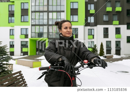 Lifestyle concept, young brunette woman walking down the street with a bike Lifestyle concept, young brunette woman walking down the street with a bike 113185836