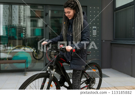 Photo on the street, a young woman took her bike for a walk in winter Photo on the street, a young woman took her bike for a walk in winter 113185882