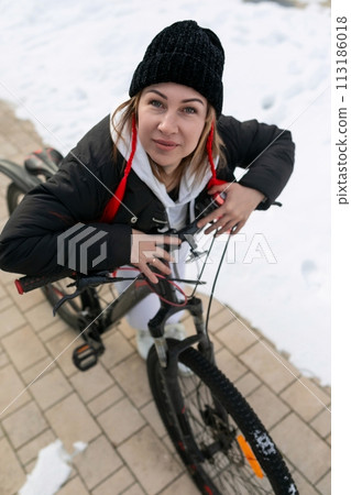 Young woman in winter clothes riding a bicycle Young woman in winter clothes riding a bicycle 113186018