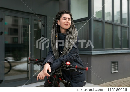 Cute young woman with dreadlocks riding a bicycle in the city Cute young woman with dreadlocks riding a bicycle in the city 113186026