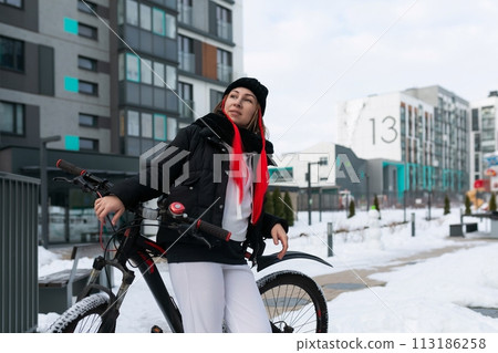 European woman in winter clothes riding a bicycle in winter 113186258