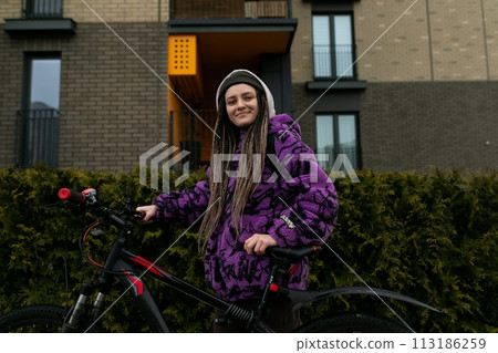 Bicycle rental concept. Young woman with dreadlocks holding a bicycle 113186259