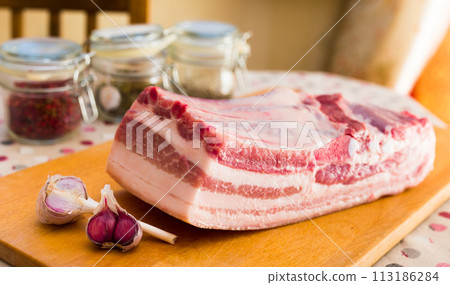 fresh piece of pork belly on wooden board with spices 113186284